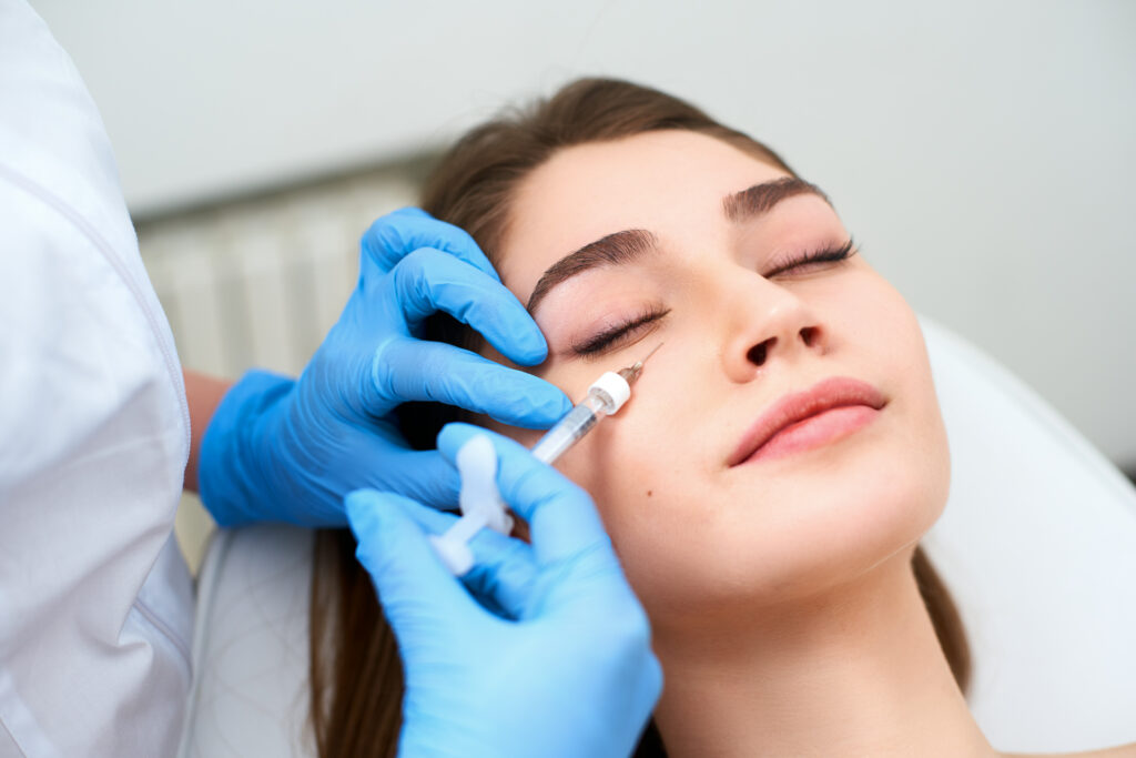 doctor in medical gloves with syringe injects botulinum under eyes for rejuvenating wrinkle treatment. 