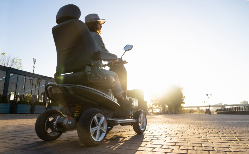 Woman riding in an electric wheelchair outdoors.