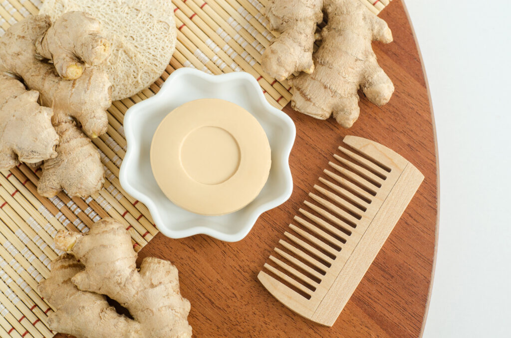 Small bowl with ginger bar soap (solid shampoo) and wooden hairbrush.